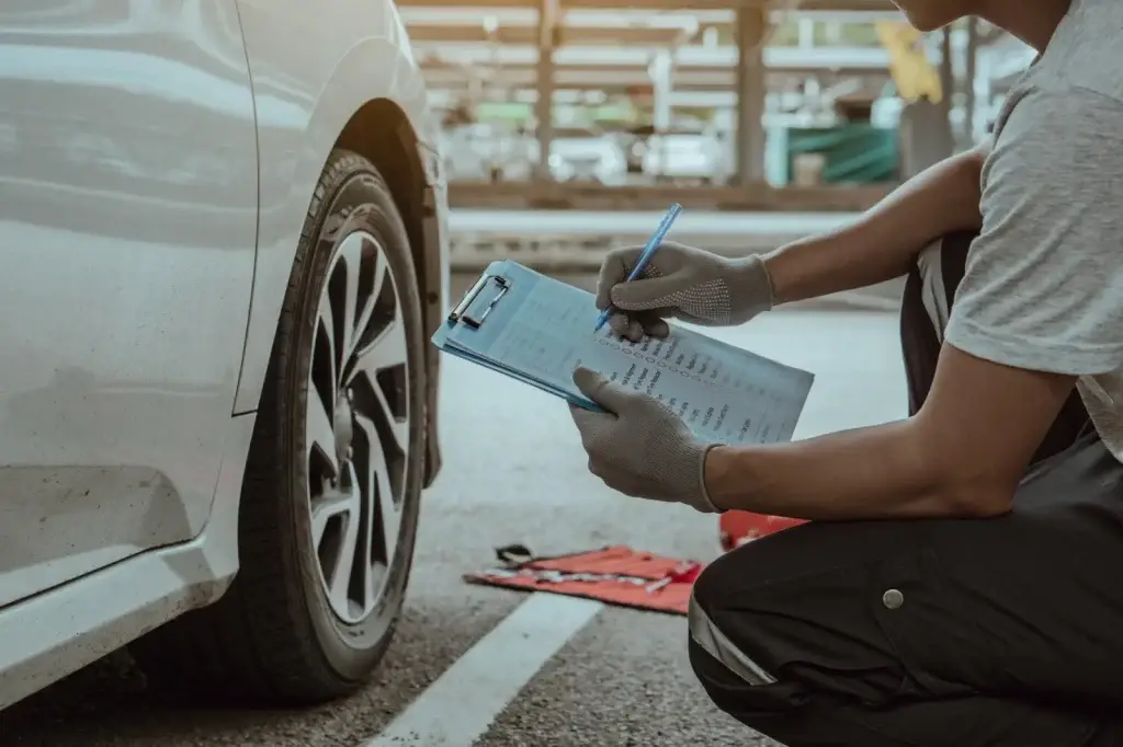 Mechanic completing a vehicle inspection checklist beside a car